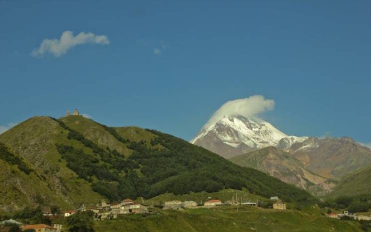  Z miasteczka Kazbegi widać już pokryty śniegiem i chmurami szczyt Kazbek o wysokości 5047m n.p.m. Nad widoczną wioską Gergeti usadowiła się światynia Cminda Sameba. Gruzini często budują swoje świątynie na wysokich górach by być bliżej Boga.