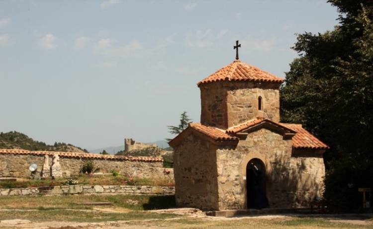 Miniaturowa cerkiew w Samtawro a w oddali widać ruiny średniowiecznej twierdzy Berbiscyche.